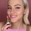 A woman holding a pink lipstick in her hand.