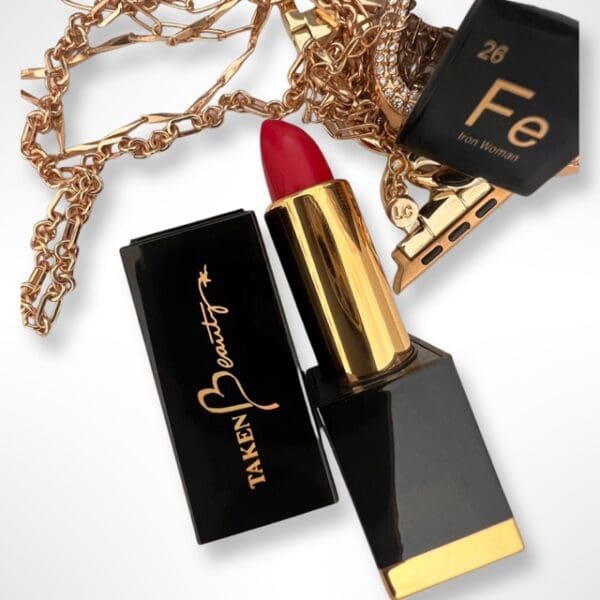 A red lipstick and gold necklace on top of white background.