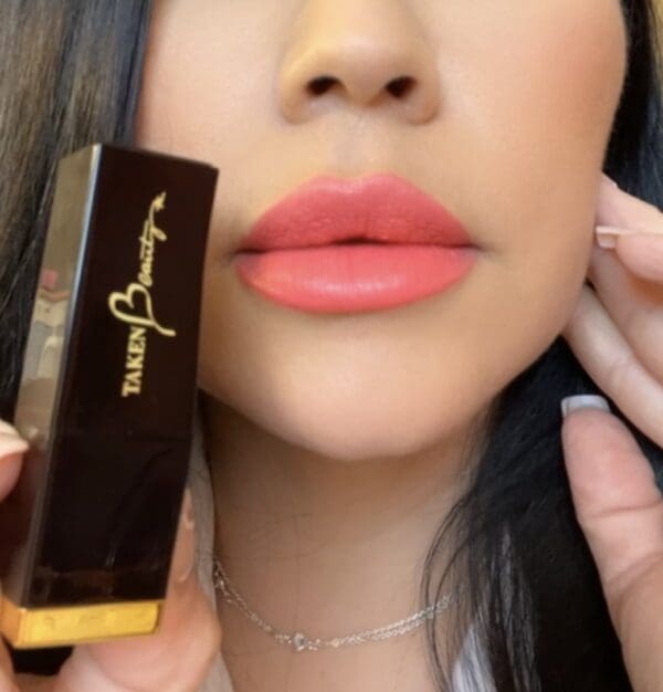 A woman holding a box of lipstick in her hand.