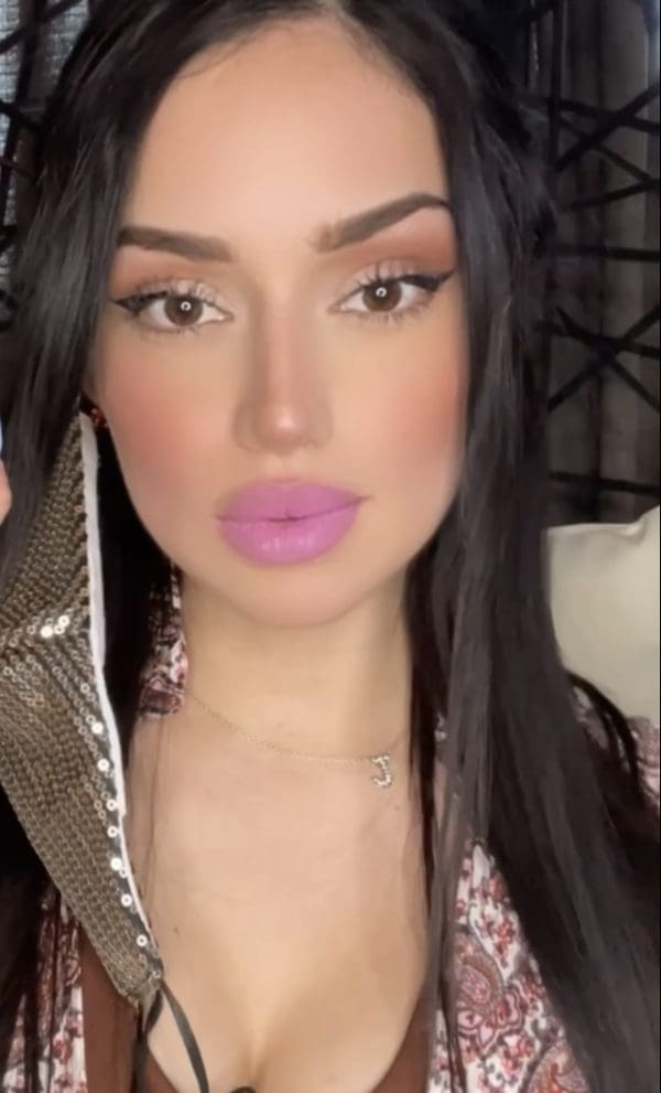 A woman with long black hair and pink lipstick.