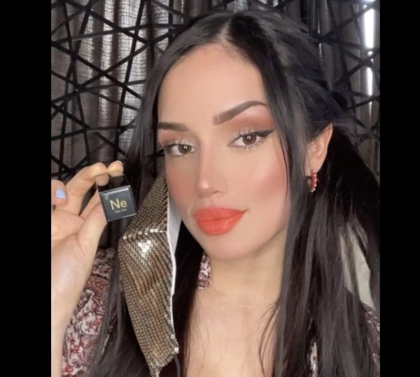 A woman holding onto a phone and wearing makeup