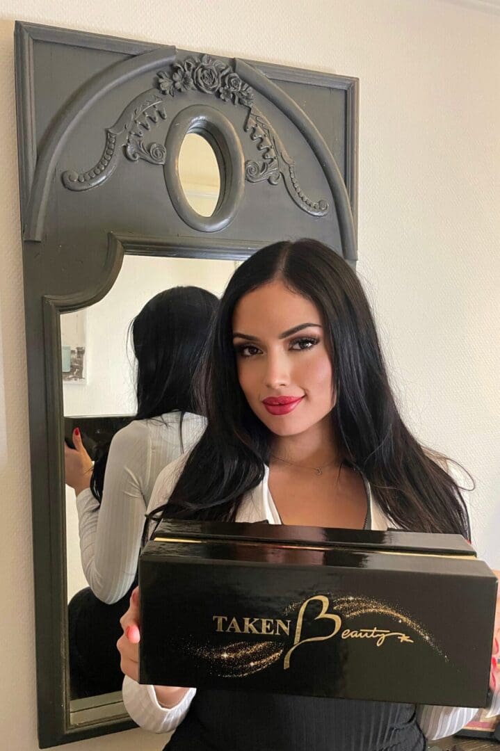 Model holding collection of TAKENBeauty lipsticks
