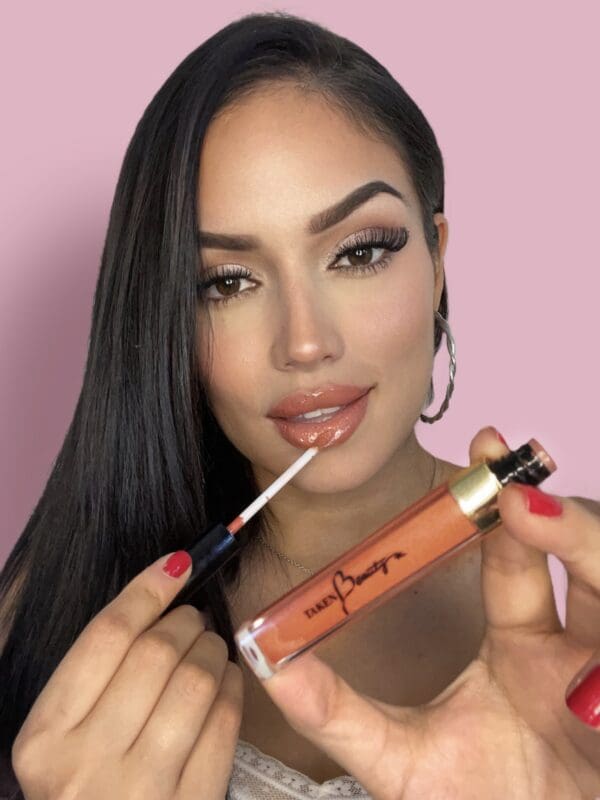 A woman is holding a lip gloss and lipstick.