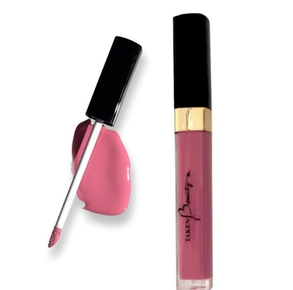 A pink lip gloss next to a black brush.