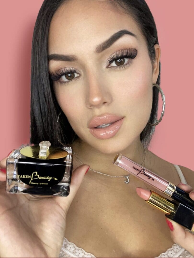 A beautiful woman holding Taken Beauty Lip Products