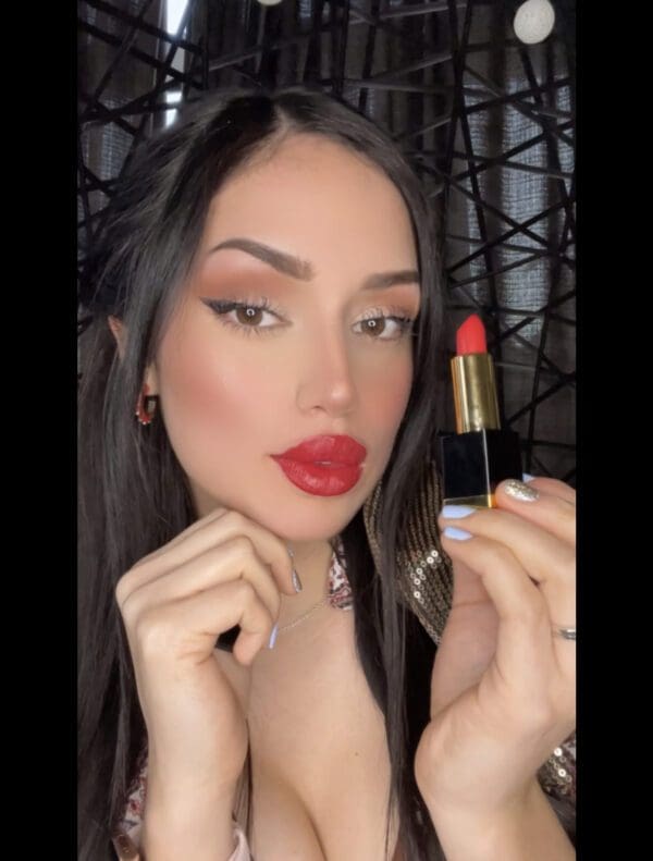 A woman holding onto a red lipstick