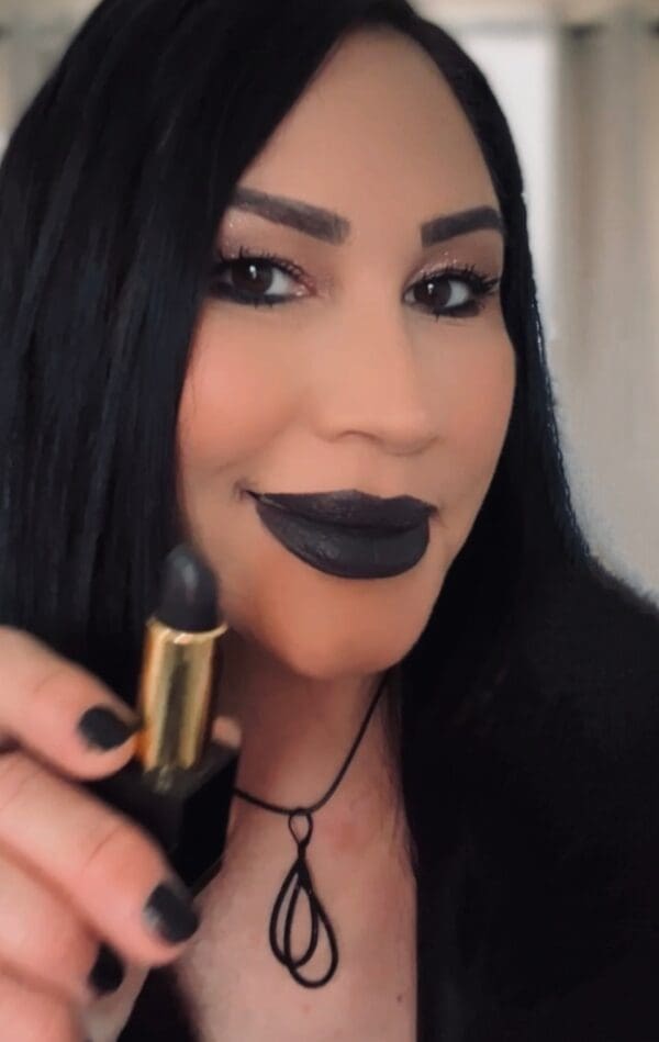 A woman holding a black lipstick in her hand.