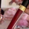 A person holding onto a red lip gloss