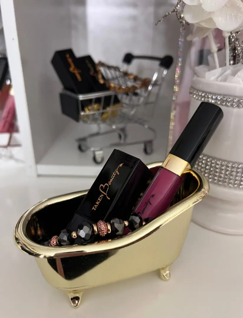 A gold bowl with lipstick and makeup on it.