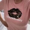 A woman wearing a pink shirt with a black and white design on it.