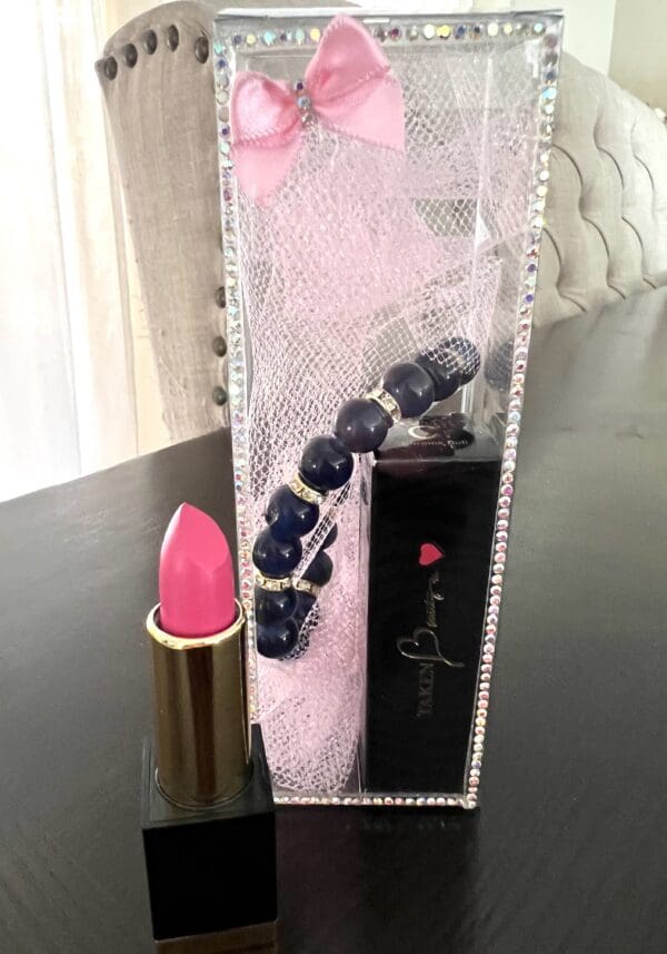 A lipstick and necklace in a box on top of a table.