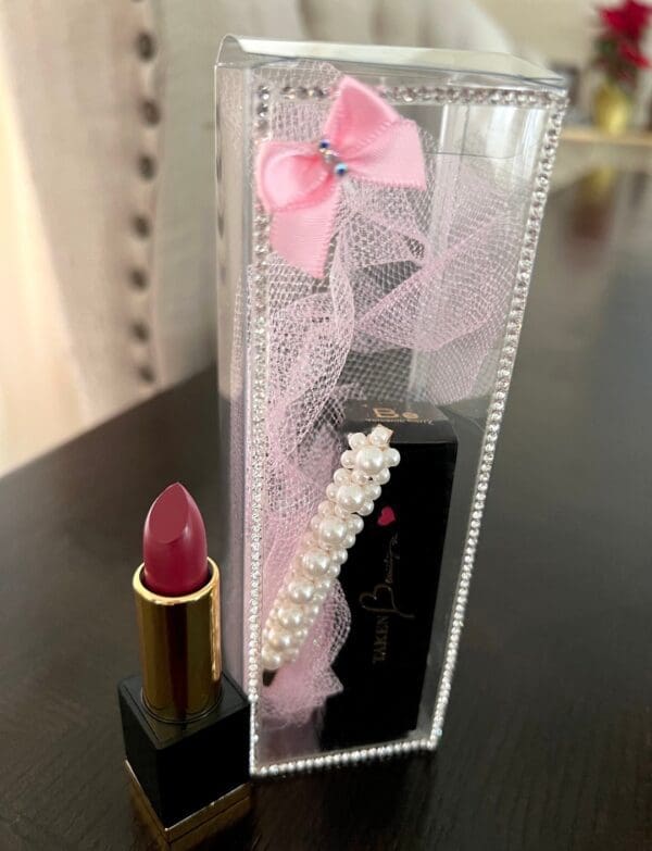 A lipstick and necklace in a clear case.