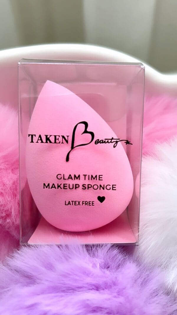 A pink beauty blender in its box on top of some fluffy material.