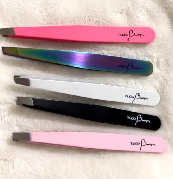 A group of five different colored tweezers on top of a white surface.
