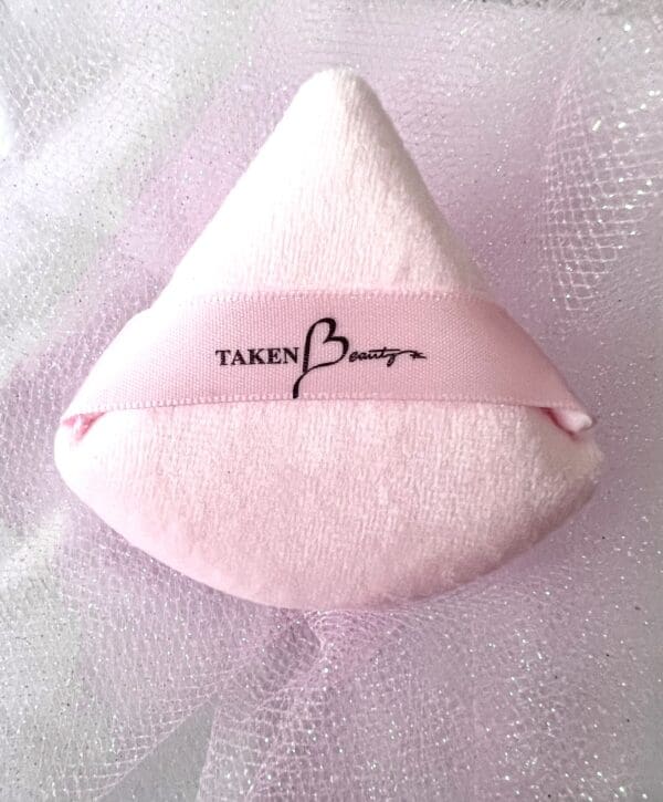 A pink pillow with the words taken by heart written on it.