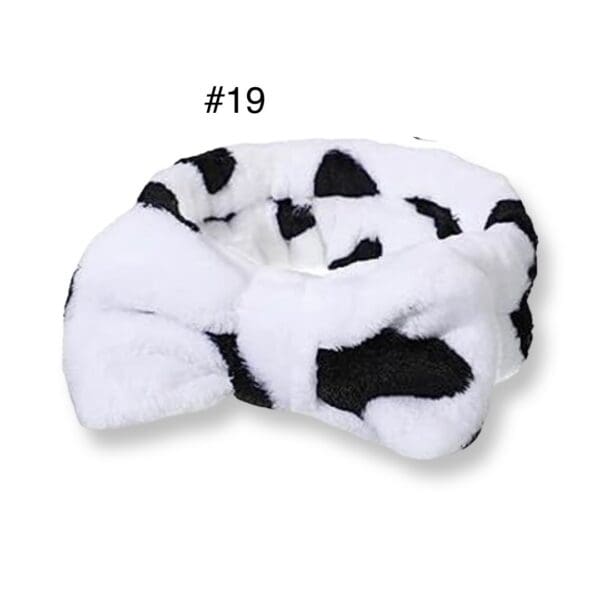 A black and white cow print headband with a bow.