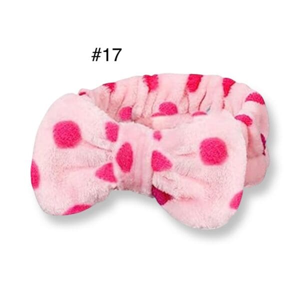 A pink polka dot headband with a bow.