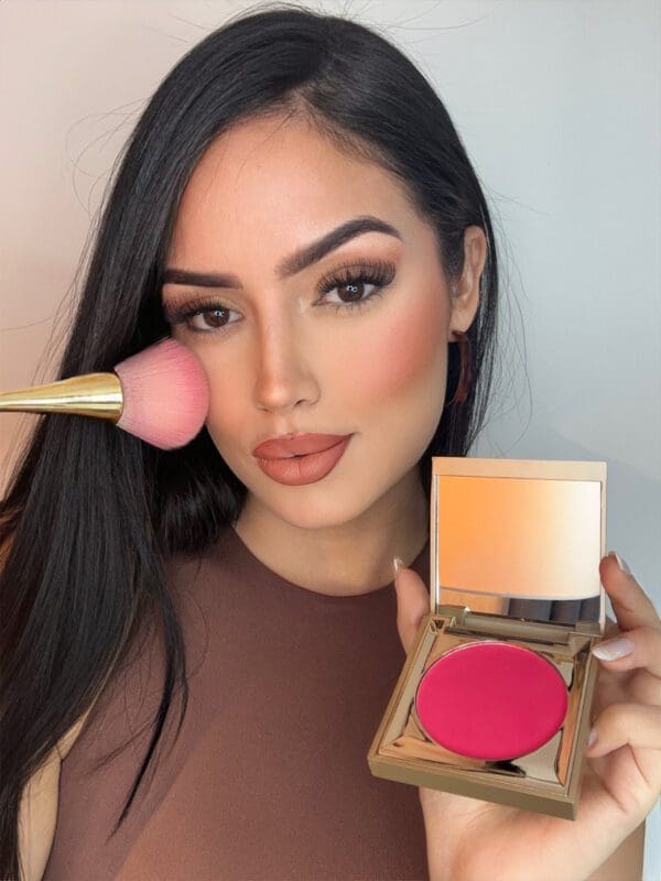 A woman holding a pink blush and a brush.