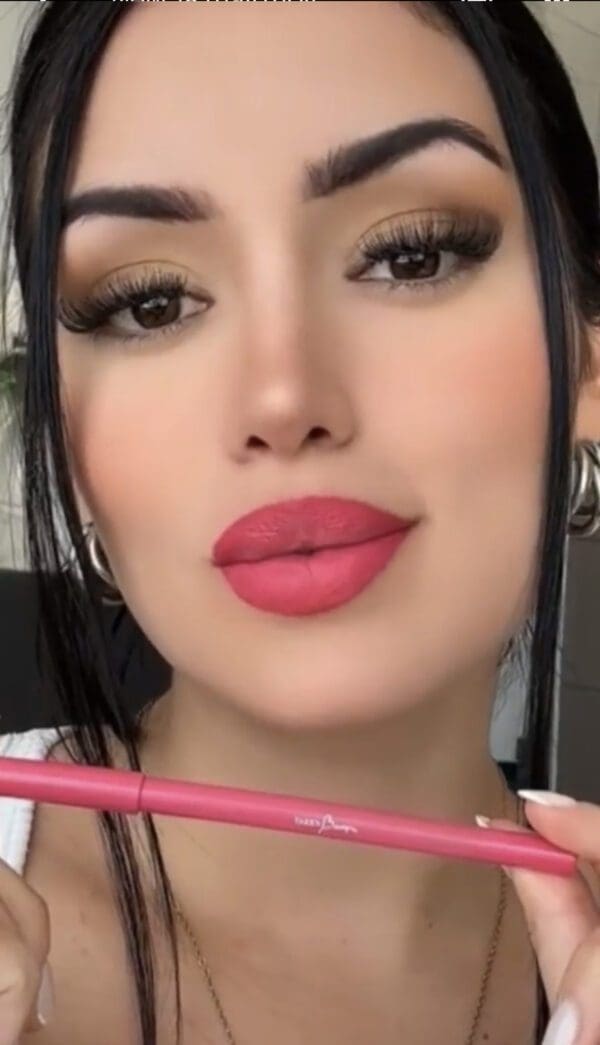 A woman with pink lipstick holding two pencils.