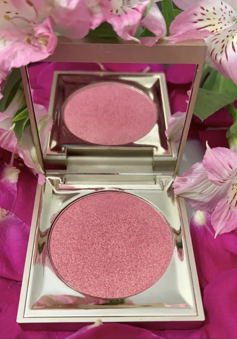 A pink compact with some flowers around it