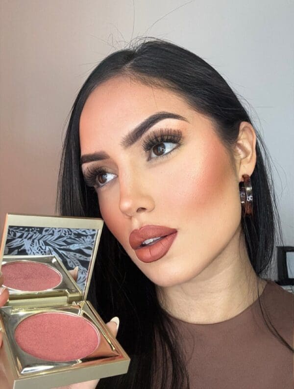 A woman holding a pink and brown makeup palette.