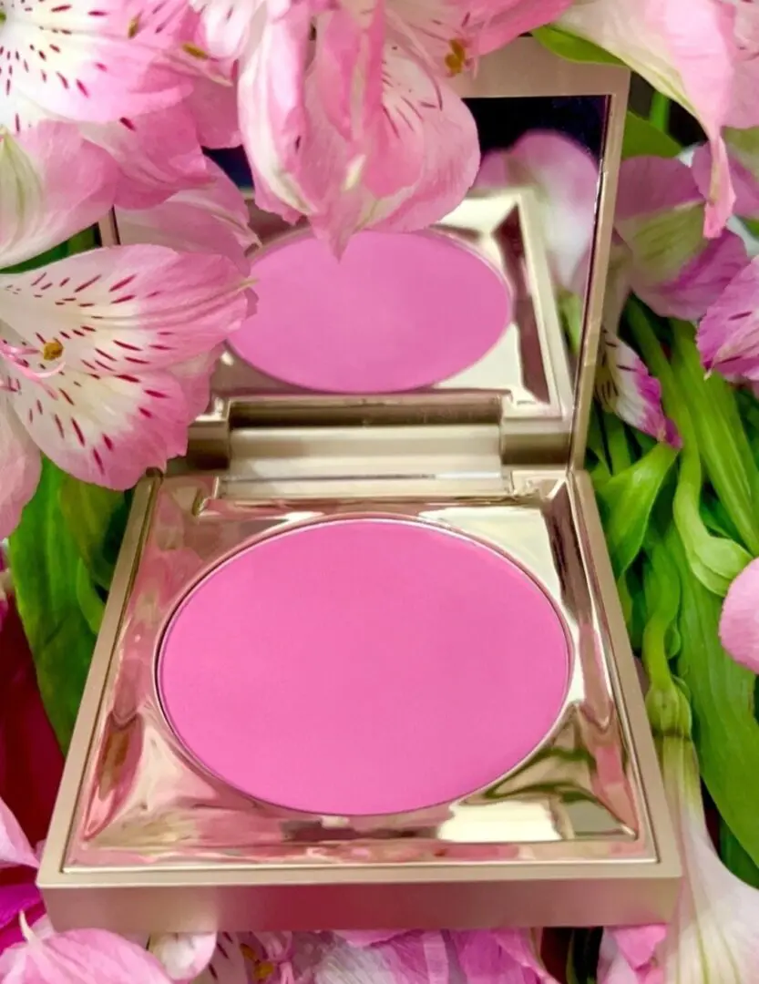 A close up of a pink powder in the mirror