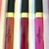 Three lipsticks in different colors are sitting on a table.