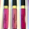 Three lipsticks in different shades of pink are sitting on a table.
